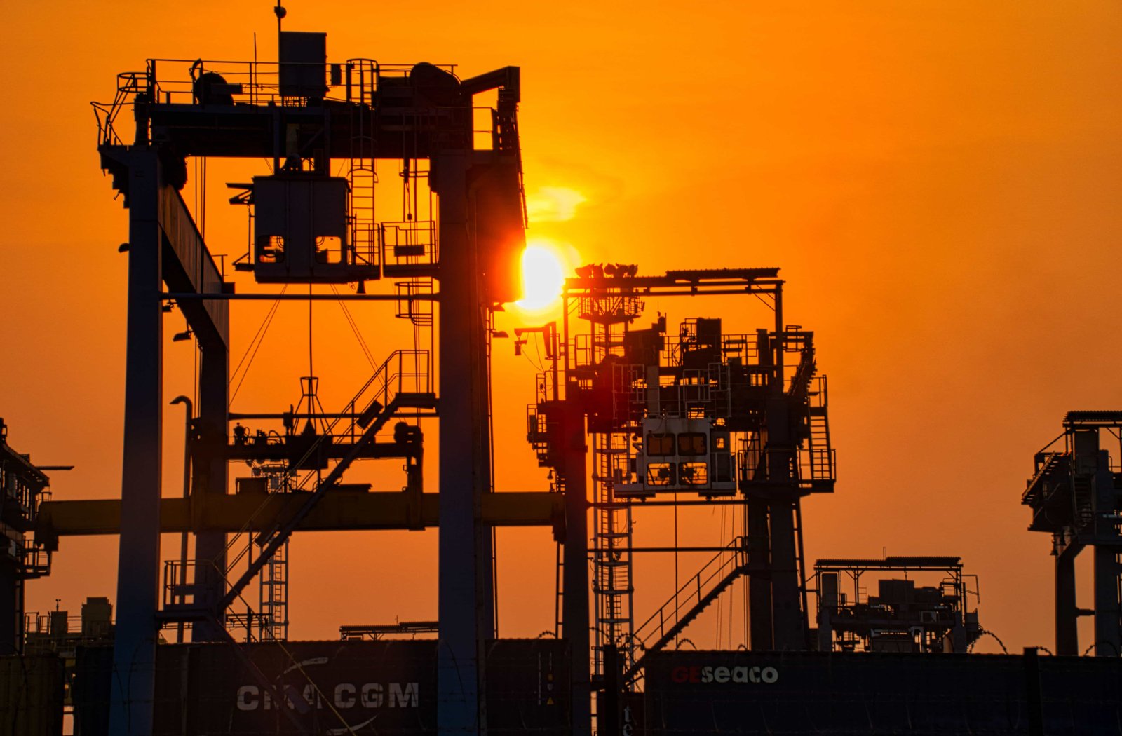 Container ship and stacked containers at a seaport at sunset